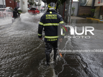 A firefighter is trying to unclog a drain after flooding is reported in various areas of Mexico City. (