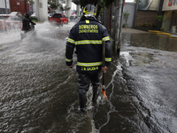 A firefighter is trying to unclog a drain after flooding is reported in various areas of Mexico City. (