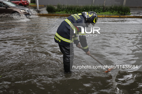 A firefighter is trying to unclog a drain after flooding is reported in various areas of Mexico City. 