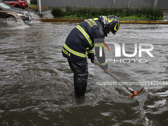 A firefighter is trying to unclog a drain after flooding is reported in various areas of Mexico City. (