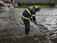 A firefighter is trying to unclog a drain after flooding is reported in various areas of Mexico City. (