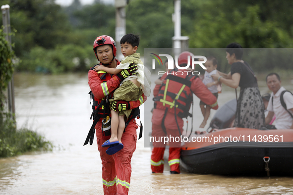 Rescue workers are moving trapped people in Jingtang village, Tangdong Subdistrict, Zixing city, Central China's Hunan province, on July 28,...