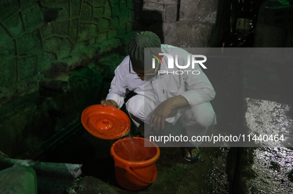 A man is filling a bucket with water on a hot summer evening in Srinagar, Jammu and Kashmir, on July 28, 2024. Kashmir is reeling under an i...