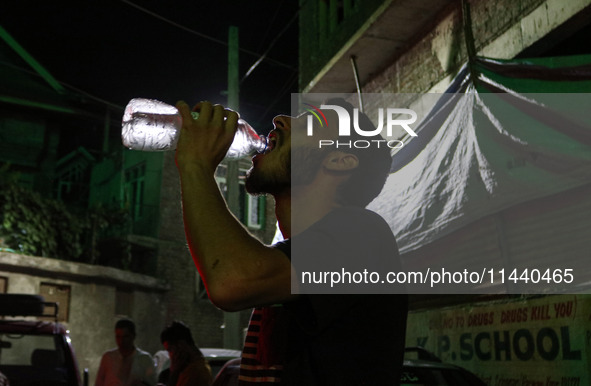 A man is drinking water outside his home on a hot summer evening in Srinagar, Jammu and Kashmir, on July 28, 2024. Kashmir is reeling under...