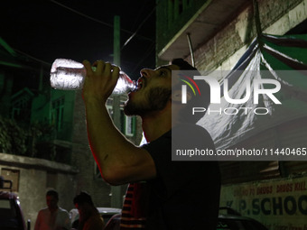 A man is drinking water outside his home on a hot summer evening in Srinagar, Jammu and Kashmir, on July 28, 2024. Kashmir is reeling under...