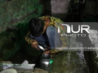 A boy is filling a steel bucket with water on a hot summer evening in Srinagar, Jammu and Kashmir, on July 28, 2024. Kashmir is reeling unde...