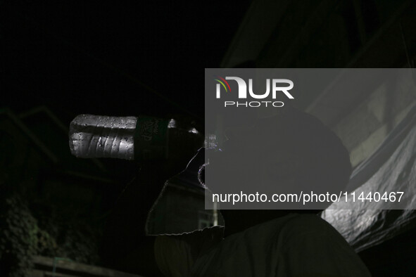 A man is drinking water outside his home on a hot summer evening in Srinagar, Jammu and Kashmir, on July 28, 2024. Kashmir is reeling under...