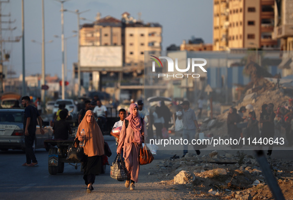 Displaced Palestinians are leaving al-Bureij refugee camp towards the west, after the Israeli army issued a new evacuation order, in the cen...