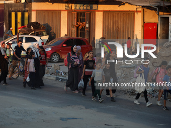 Displaced Palestinians are leaving al-Bureij refugee camp towards the west, after the Israeli army issued a new evacuation order, in the cen...