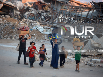 Displaced Palestinians are leaving al-Bureij refugee camp towards the west, after the Israeli army issued a new evacuation order, in the cen...