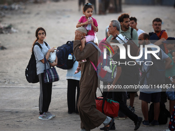 Displaced Palestinians are leaving al-Bureij refugee camp towards the west, after the Israeli army issued a new evacuation order, in the cen...