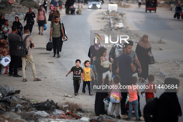 Displaced Palestinians are leaving al-Bureij refugee camp towards the west, after the Israeli army issued a new evacuation order, in the cen...