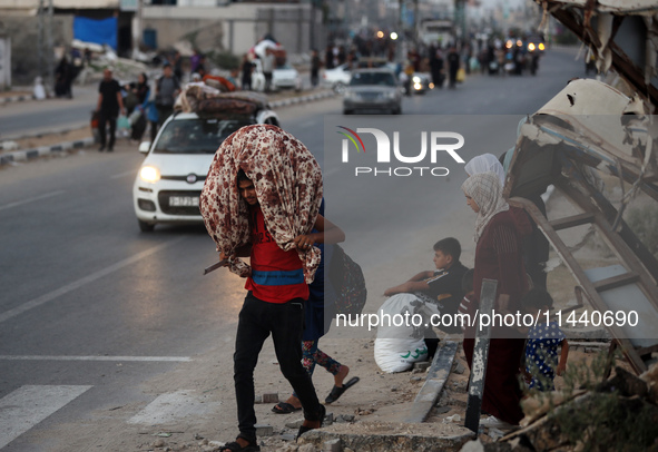 Displaced Palestinians are leaving al-Bureij refugee camp towards the west, after the Israeli army issued a new evacuation order, in the cen...