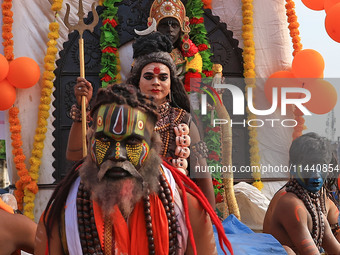 An artist is dressing up as Lord Shiva while kanwariyas are carrying holy water from the shrine 'Galta Peeth Tirtha' and going back to their...