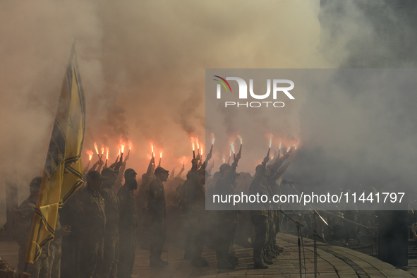 Servicemen of the Azov battalion are lighting flares as they attend a ceremony to remember the victims of the Olenivka camp explosion, in Ky...