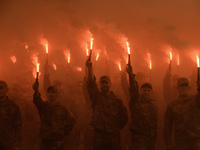 Servicemen of the Azov battalion are lighting flares as they attend a ceremony to remember the victims of the Olenivka camp explosion, in Ky...