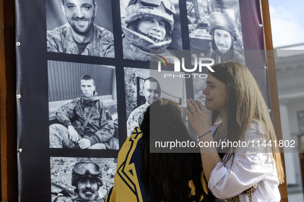 People are reacting as they are attending a ceremony to remember the victims of the Olenivka camp explosion, in Kyiv, Ukraine, on July 28, 2...