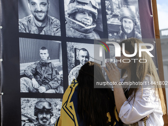 People are reacting as they are attending a ceremony to remember the victims of the Olenivka camp explosion, in Kyiv, Ukraine, on July 28, 2...