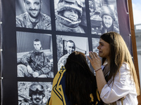 People are reacting as they are attending a ceremony to remember the victims of the Olenivka camp explosion, in Kyiv, Ukraine, on July 28, 2...