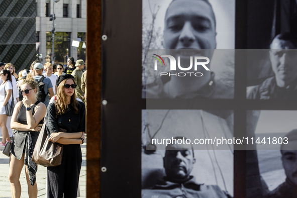 People are reacting as they are attending a ceremony to remember the victims of the Olenivka camp explosion, in Kyiv, Ukraine, on July 28, 2...