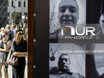 People are reacting as they are attending a ceremony to remember the victims of the Olenivka camp explosion, in Kyiv, Ukraine, on July 28, 2...