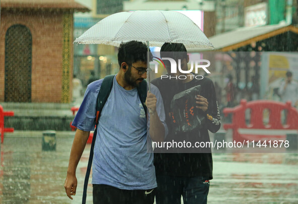 People are walking along a street as it is raining in Srinagar, Jammu and Kashmir, on July 29, 2024. 