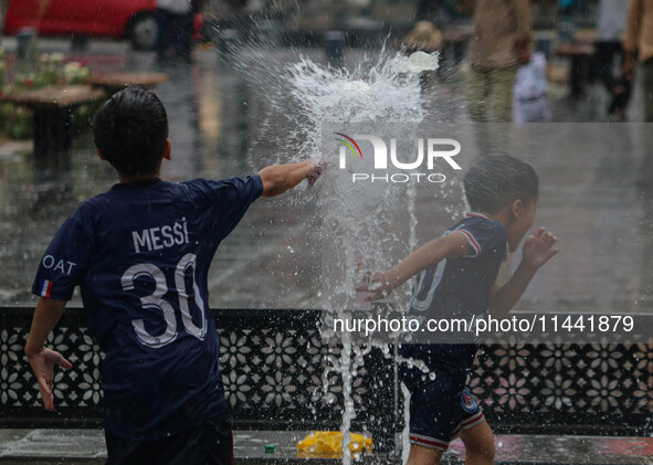 Children are playing with fountain water as it is raining in Srinagar, Jammu and Kashmir, on July 29, 2024. 