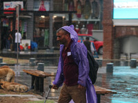 A man is wearing a raincoat and walking along a street as it is raining in Srinagar, Jammu and Kashmir, on July 29, 2024. (