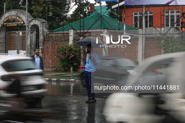 A traffic police officer is holding an umbrella and controlling the traffic system as it is raining in Srinagar, Jammu and Kashmir, on July...