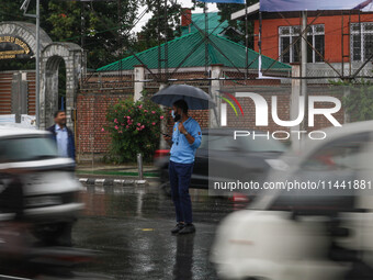 A traffic police officer is holding an umbrella and controlling the traffic system as it is raining in Srinagar, Jammu and Kashmir, on July...