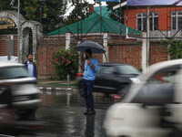 A traffic police officer is holding an umbrella and controlling the traffic system as it is raining in Srinagar, Jammu and Kashmir, on July...