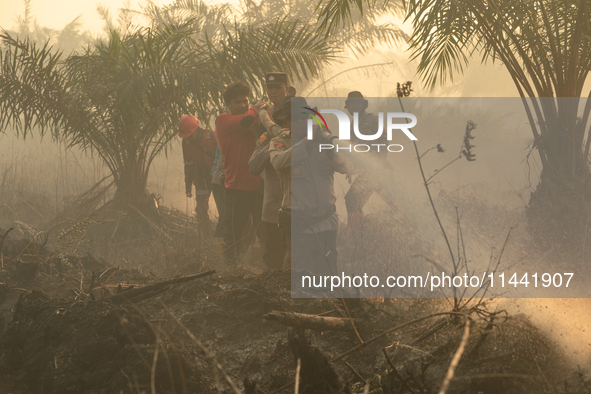 Indonesian police officers are trying to extinguish a peatland fire in the palm oil plantation area of Company Permata Hijau Indonesia in Pa...