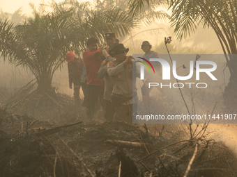 Indonesian police officers are trying to extinguish a peatland fire in the palm oil plantation area of Company Permata Hijau Indonesia in Pa...