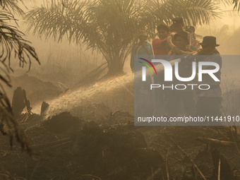 Indonesian police officers are trying to extinguish a peatland fire in the palm oil plantation area of Company Permata Hijau Indonesia in Pa...