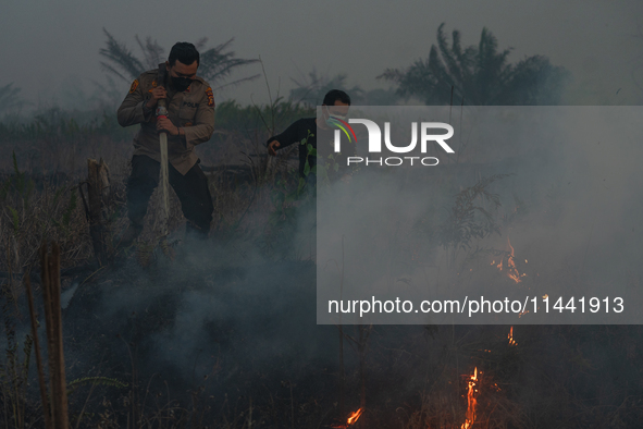 Indonesian police officers are trying to extinguish a peatland fire in the palm oil plantation area of Company Permata Hijau Indonesia in Pa...