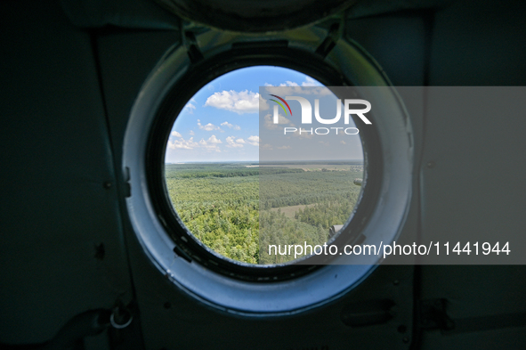 A landscape is being seen through a porthole of a Mi-8MSB-V assault transport helicopter of the 16th Brody Separate Army Aviation Brigade in...