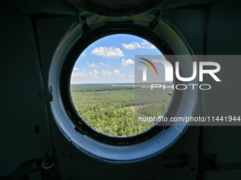 A landscape is being seen through a porthole of a Mi-8MSB-V assault transport helicopter of the 16th Brody Separate Army Aviation Brigade in...