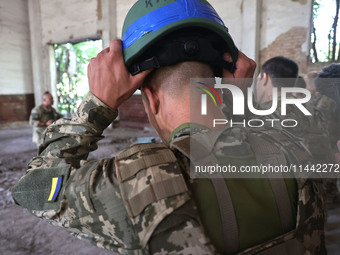 A Shkval (Squall) Battalion serviceman is holding a helmet during drills in Ukraine, on July 26, 2024. Former prisoners who volunteered to d...