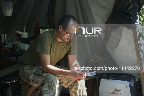 A Shkval (Squall) Battalion serviceman is using a smartphone in Ukraine, on July 26, 2024. Former prisoners who volunteered to defend Ukrain...