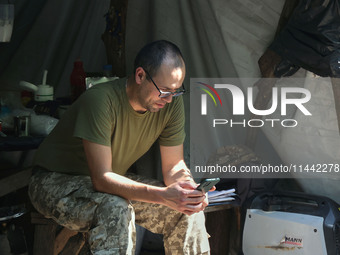 A Shkval (Squall) Battalion serviceman is using a smartphone in Ukraine, on July 26, 2024. Former prisoners who volunteered to defend Ukrain...