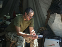 A Shkval (Squall) Battalion serviceman is using a smartphone in Ukraine, on July 26, 2024. Former prisoners who volunteered to defend Ukrain...