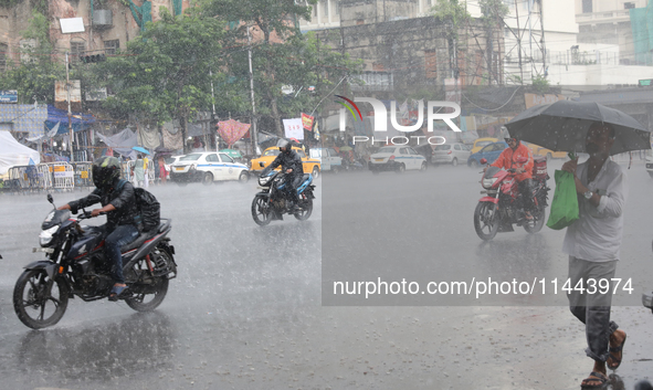 Commuters are crossing a road during heavy monsoon rain in Kolkata, India, on July 30, 2024. 