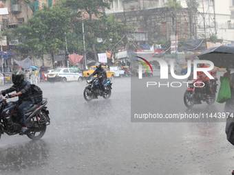 Commuters are crossing a road during heavy monsoon rain in Kolkata, India, on July 30, 2024. (