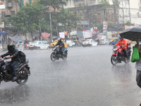 Commuters are crossing a road during heavy monsoon rain in Kolkata, India, on July 30, 2024. (