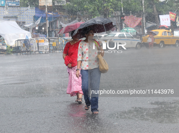 Women are crossing a road during heavy monsoon rain in Kolkata, eastern India, on July 30, 2024. 