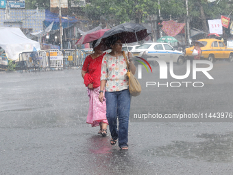 Women are crossing a road during heavy monsoon rain in Kolkata, eastern India, on July 30, 2024. (