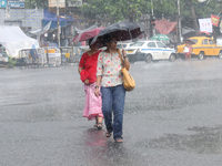 Women are crossing a road during heavy monsoon rain in Kolkata, eastern India, on July 30, 2024. (