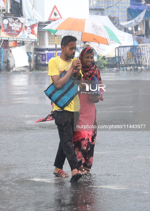 Commuters are crossing a road during heavy monsoon rain in Kolkata, eastern India, on July 30, 2024 