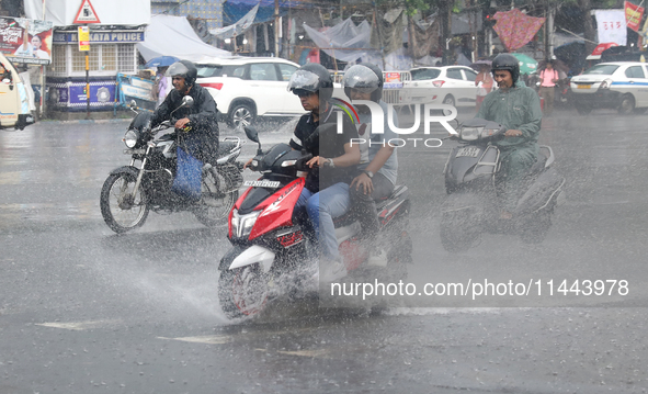 Commuters are crossing a road during heavy monsoon rain in Kolkata, eastern India, on July 30, 2024 