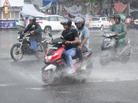 Commuters are crossing a road during heavy monsoon rain in Kolkata, eastern India, on July 30, 2024 (